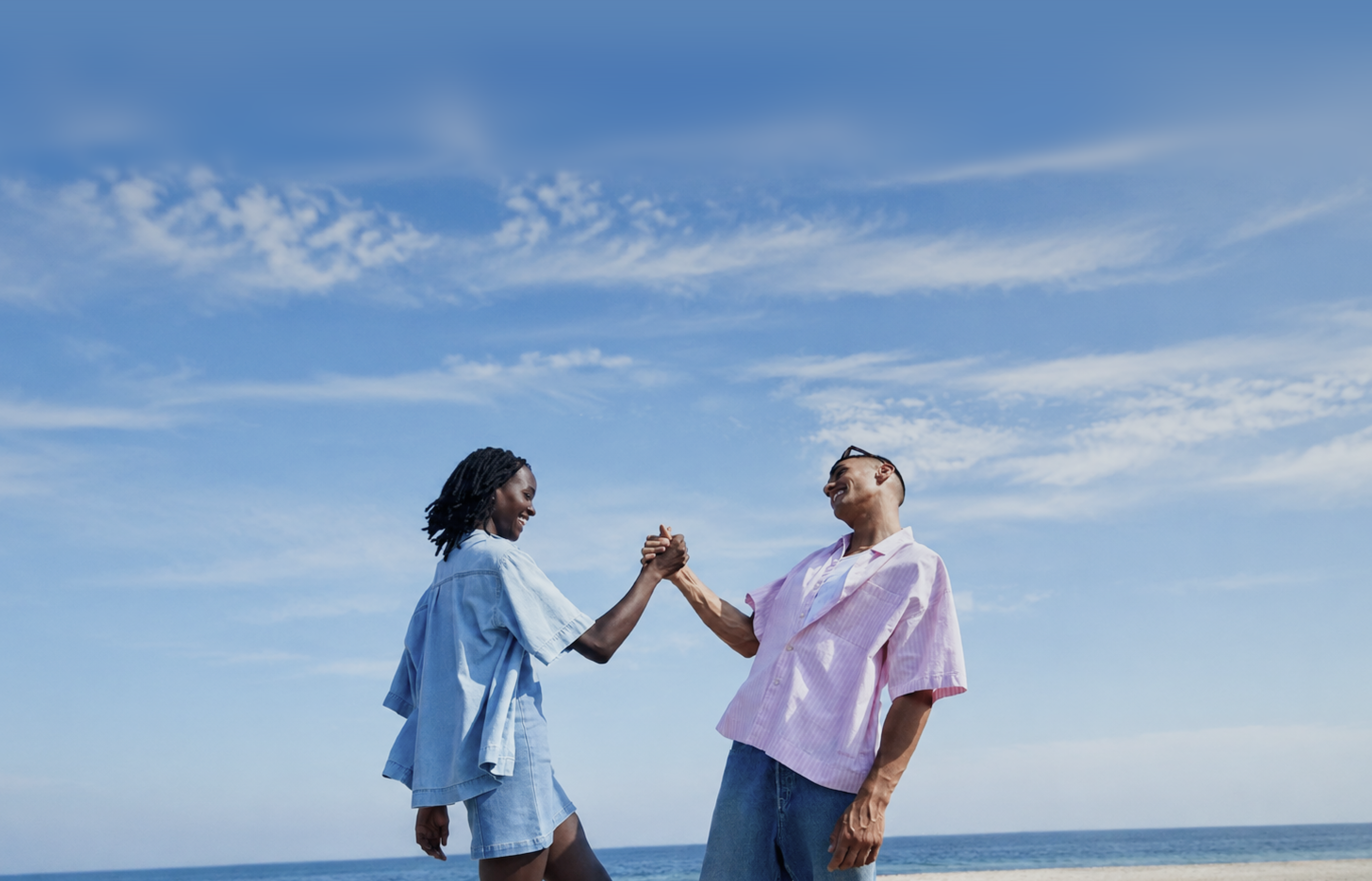 Two people clasping hands under a blue sky